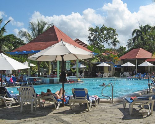An outdoor swimming pool with chaise lounge chairs and umbrellas.