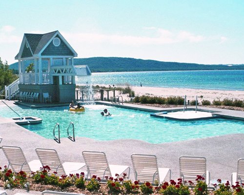 A scenic outdoor swimming pool and hot tub with chaise lounge chairs alongside the lake.