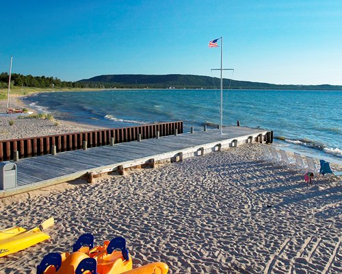 View of the lake with wooden pier and chaise lounge chairs.