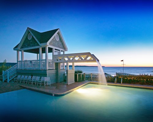 An outdoor swimming pool with a waterfall alongside the beach.