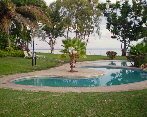 An outdoor swimming pool with chaise lounge chairs alongside the lake.