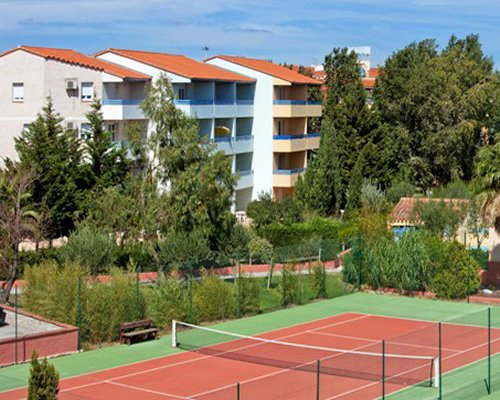 An outdoor tennis court alongside the multi story resort.