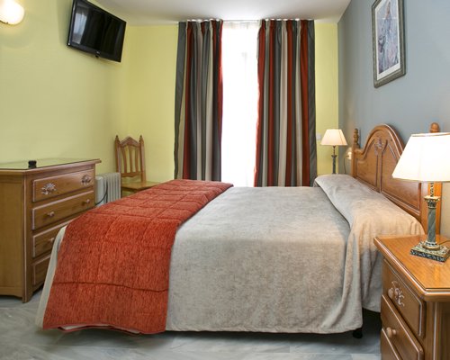 A well furnished bedroom with a double bed and a television.