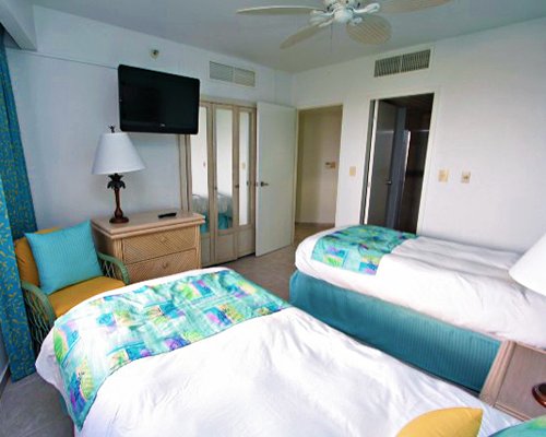 A well furnished bedroom with two twin beds and a television.