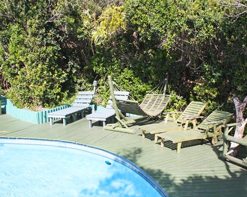 An outdoor swimming pool with chaise lounge chairs and a hammock.