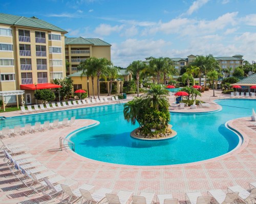 A SCENIC OUTDOOR SWIMMING POOL WITH CHAISE LOUNGE CHAIRS AND SUNSHADES ALONGSIDE THE RESORT.