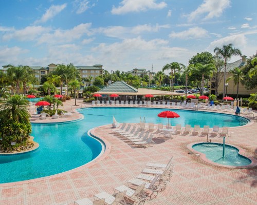 AN OUTDOOR SWIMMING POOL AND KIDDIE POOL WITH CHAISE LOUNGE CHAIRS.