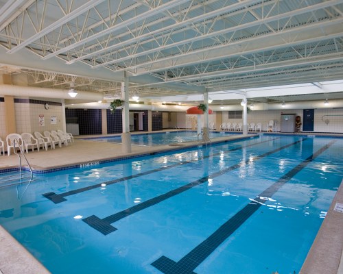 AN INDOOR SWIMMING POOL WITH PATIO CHAIRS.