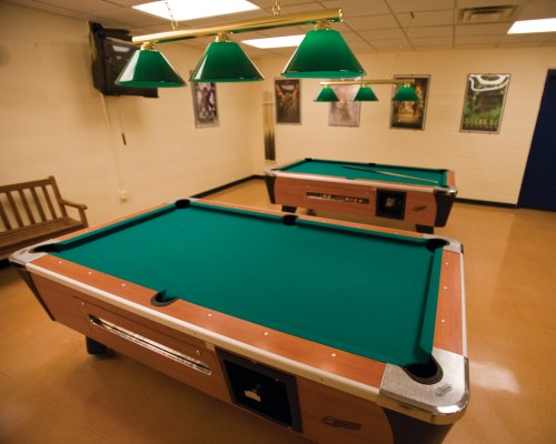 AN INDOOR RECREATIONAL ROOM WITH POOL TABLES.