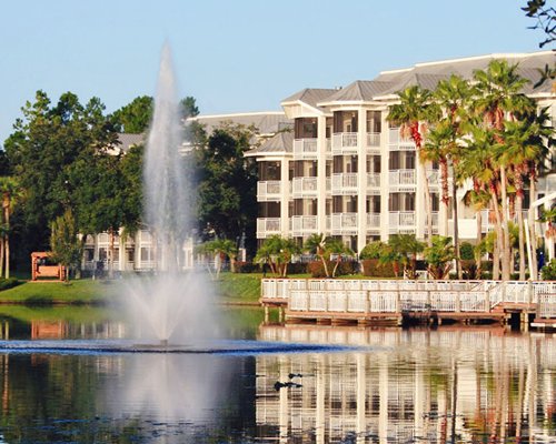 A view of the water accompanied by a  fountain alongside the multi story resort units.
