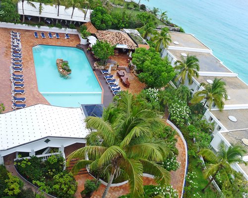 An aerial view of the swimming pool with chaise lounge chairs alongside multiple resort units.