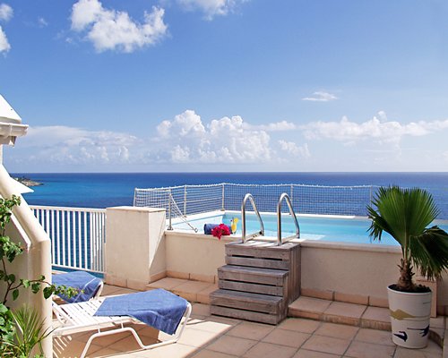 An outdoor swimming pool with chaise lounge chairs alongside the ocean.