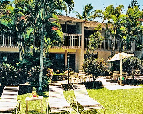 Scenic exterior view of multiple unit balconies with chaise lounge chairs and sunshade.