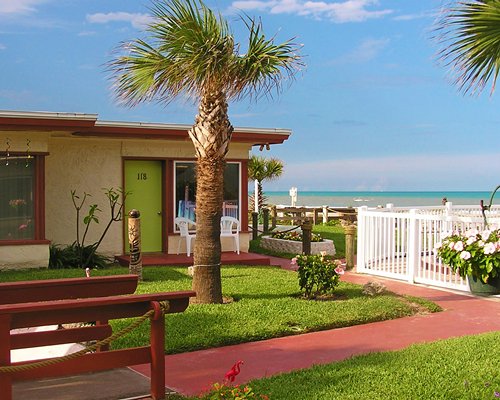 Scenic exterior view of a resort unit with patio furniture alongside the beach.