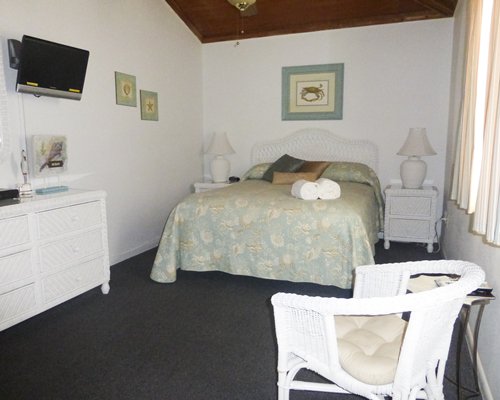 A well furnished bedroom with queen bed television and outside view.