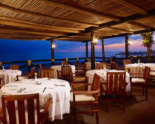 An indoor fine dining restaurant with an ocean view at dusk.