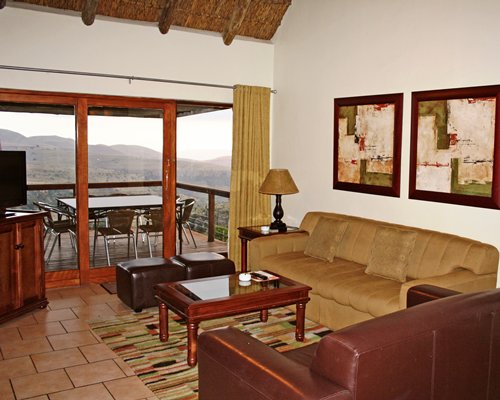 A well furnished living room with television and patio furniture in the balcony.