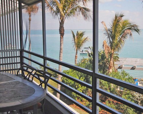 A balcony view of the ocean with patio furniture.