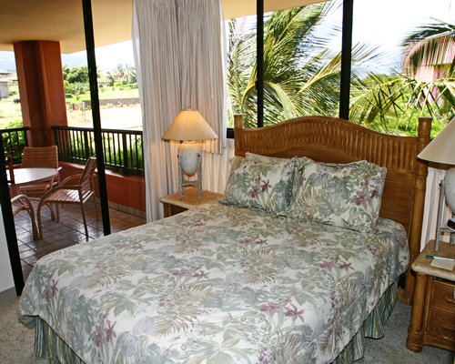 A well furnished bedroom with a queen bed and balcony.