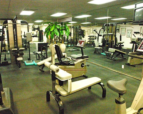 A well equipped indoor fitness area with a television.