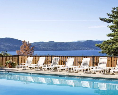 An outdoor swimming pool with chaise lounge chairs alongside the lake.