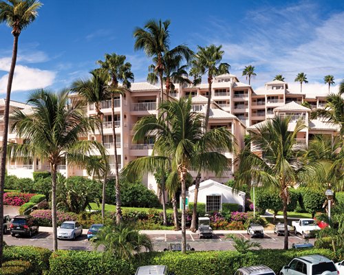 Exterior view of Elysian Beach Resort with parking lot and palm trees.