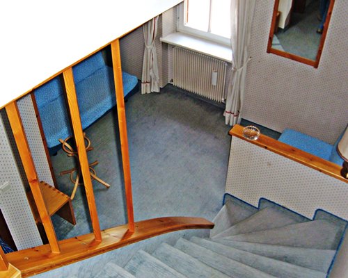 An aerial view of a living room alongside the wooden staircase.
