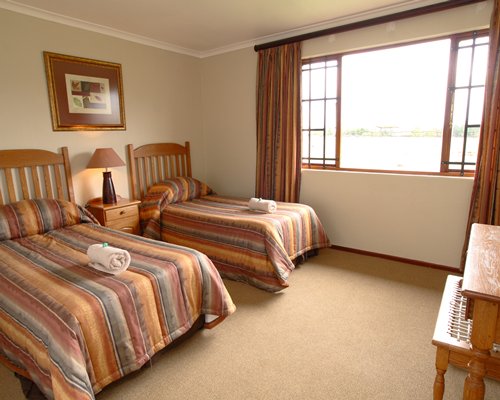 A well furnished bedroom with two beds and an outside view.