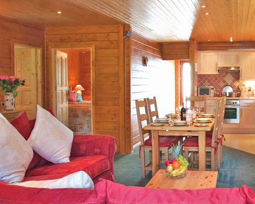 An open plan well furnished living room with a wooden dining and kitchen area.