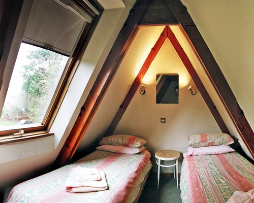 A furnished bedroom with two beds and an outside view.
