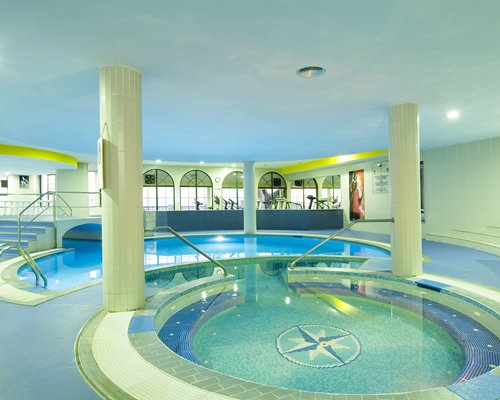 Indoor swimming pool and hot tub with outside view.