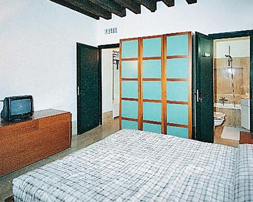 A well furnished bedroom with a television alongside a bathroom.