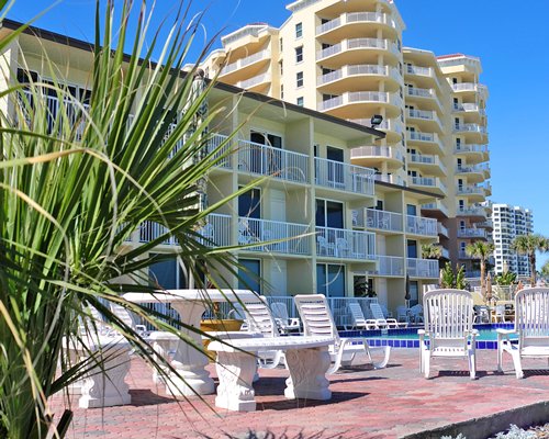 Exterior view of multiple unit balconies with outdoor swimming pool and chaise lounge chairs.