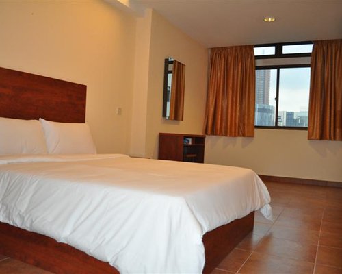 A well furnished bedroom with queen bed and outside view.
