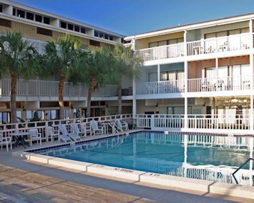 An outdoor swimming pool with patio furniture alongside multi story resort condos.