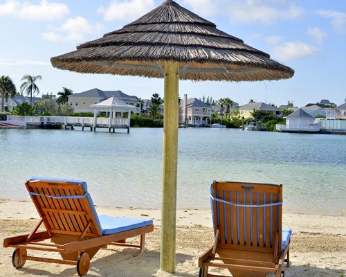 A view of lounge chairs with thatched sunshade facing the beach.
