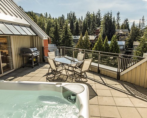 An outdoor swimming pool and a hot tub with chaise lounge chairs alongside the multi story units.