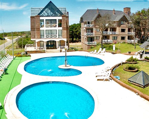An outdoor swimming pool with chaise lounge chairs and a hot tub alongside resort units.