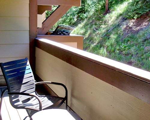 Balcony with patio chair alongside landscaped area.