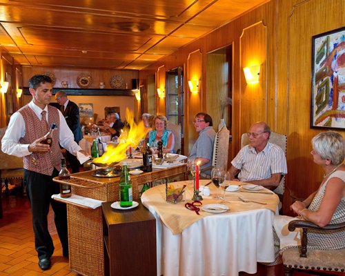 A fine dining restaurant interior with server preparing flambe at a table.