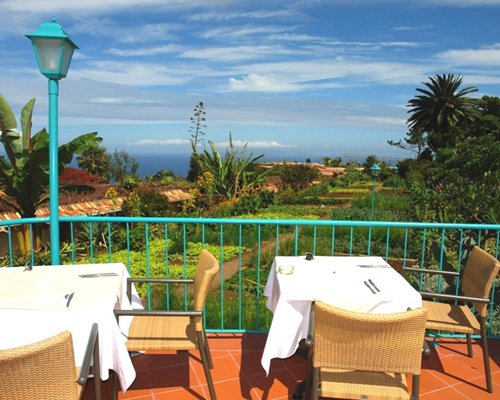 Outdoor dining tables on terrace with garden view.