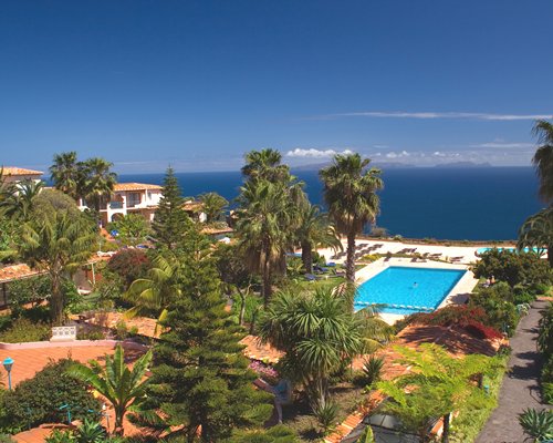 An landscaped exterior with gardens swimming pool and water view.