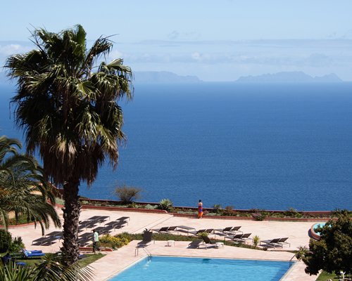 View of outdoor pool chaise lounge chairs and large body of water.