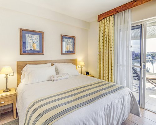 A well furnished bedroom with a balcony and chaise lounge chair.