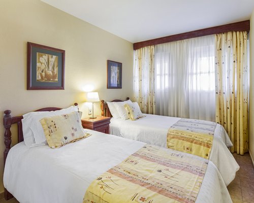 A well furnished bedroom with two twin beds and outside view.