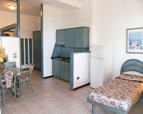An open plan kitchen with dining area and a twin bed.
