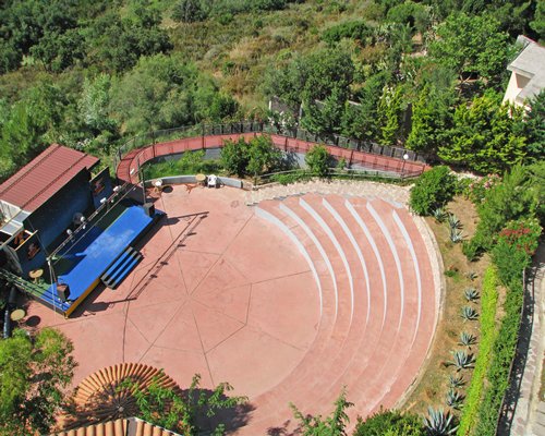 An aerial view of an outdoor venue with a stage alongside wooded area.