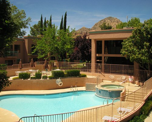 Outdoor swimming pool with a hot tub and chaise lounge chairs.