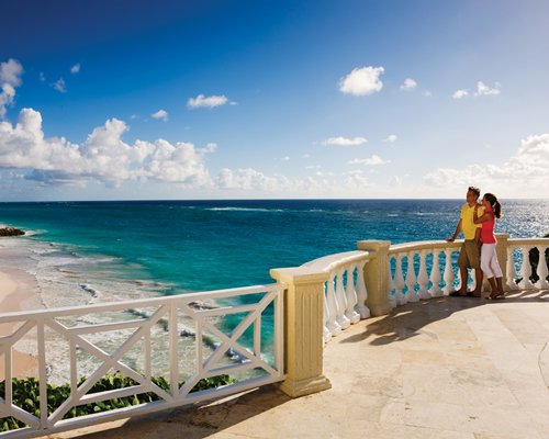 A couple standing in the balcony and facing the beach.
