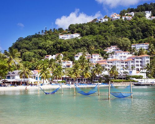 Multiple sea hammocks in the Caribbean waters alongside multiple resort condos.